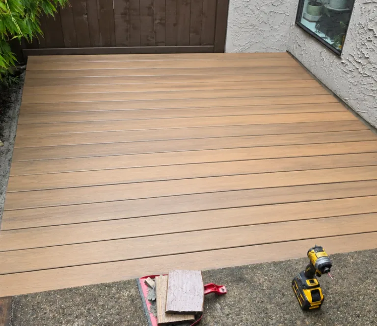 New composite decking installed in place of the old wood deck in North Vancouver, with a fence and a window beside it