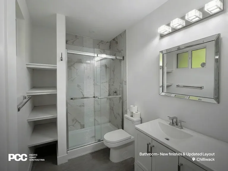 An updated bathroom renovation by Pacific Coast Contracting in Chilliwack featuring a glass-enclosed shower with marble-patterned tile, a modern white vanity, integrated open shelving, and a decorative mirrored medicine cabinet by PCC.