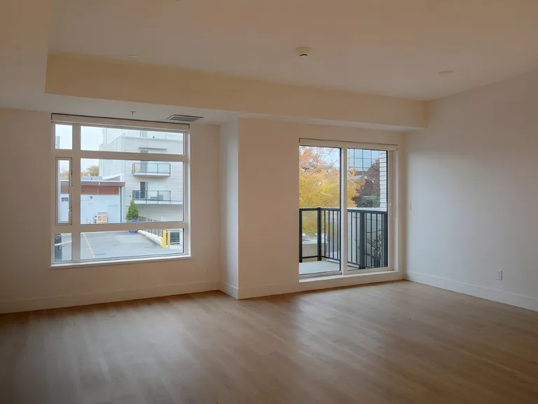 Bright open living space with new light wood flooring and large windows in a renovated Langley, BC condo by PCC Renovations.