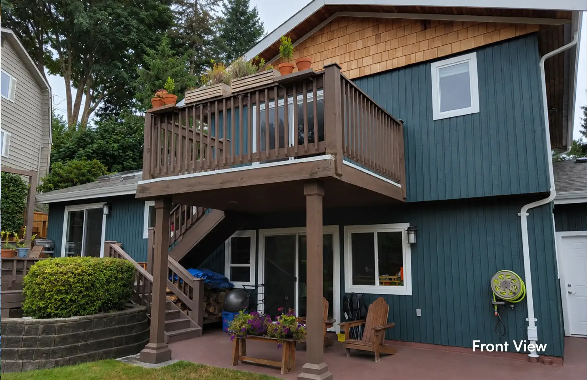 Angled view of an existing Coquitlam home's exterior and wooden deck prior to a major renovation and structural second-story extension by PCC Renovations.