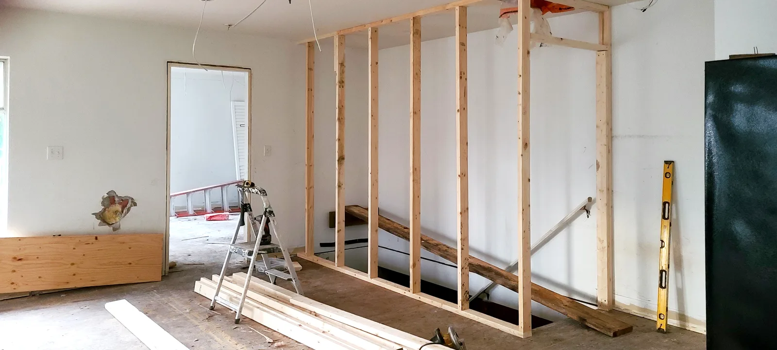 New interior wall framing with wood studs in an open living area during a house flip renovation in Maple Ridge, BC, by PCC Renovations.