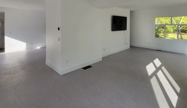 Open finished living area with white walls, new flooring and a wall-mounted TV after an interior renovation in Maple Ridge, BC by PCC Renovations.