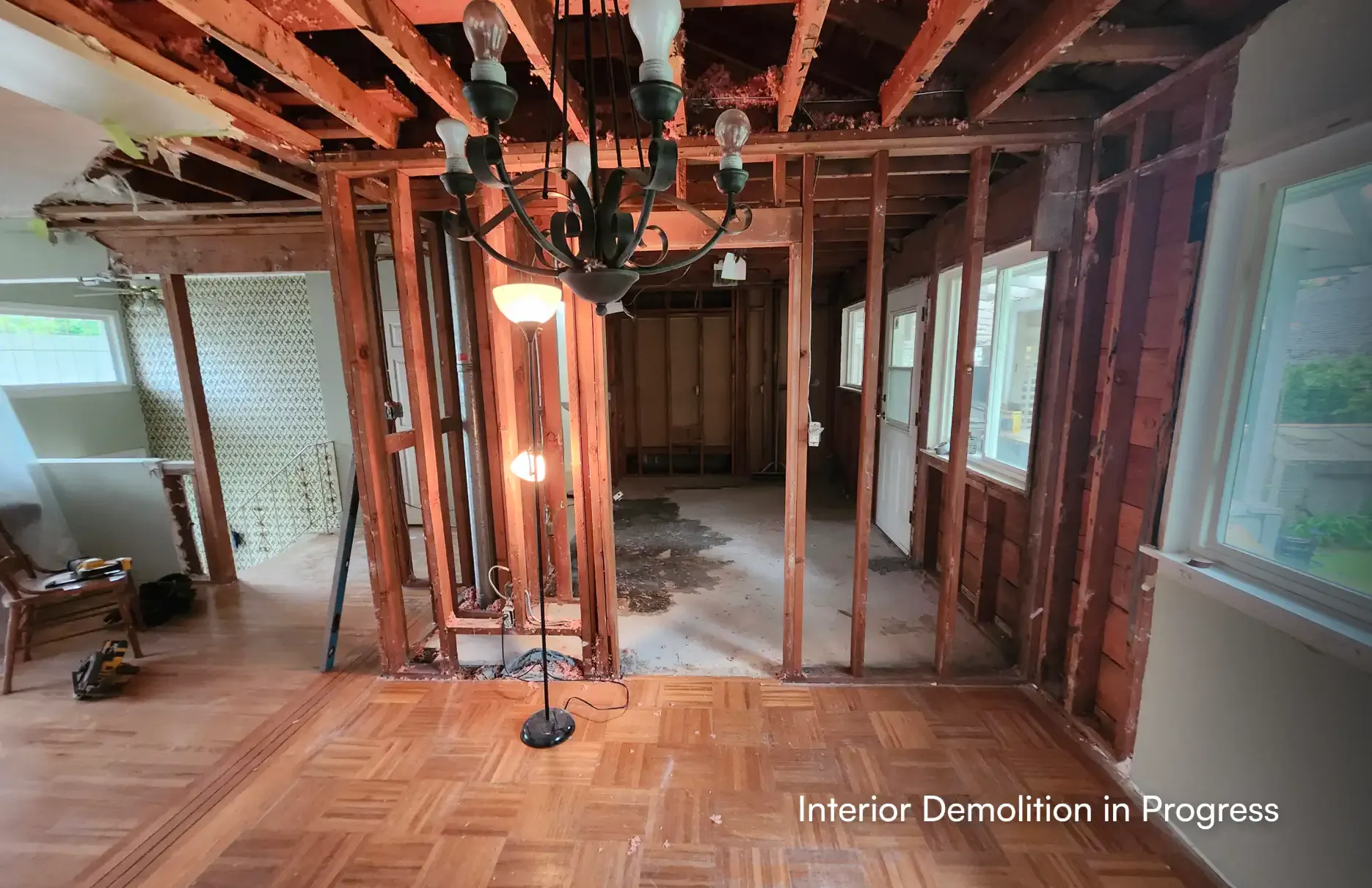 Wide view of interior demolition in progress, revealing exposed wood wall studs and ceiling joists during a home renovation in Maple Ridge by PCC.