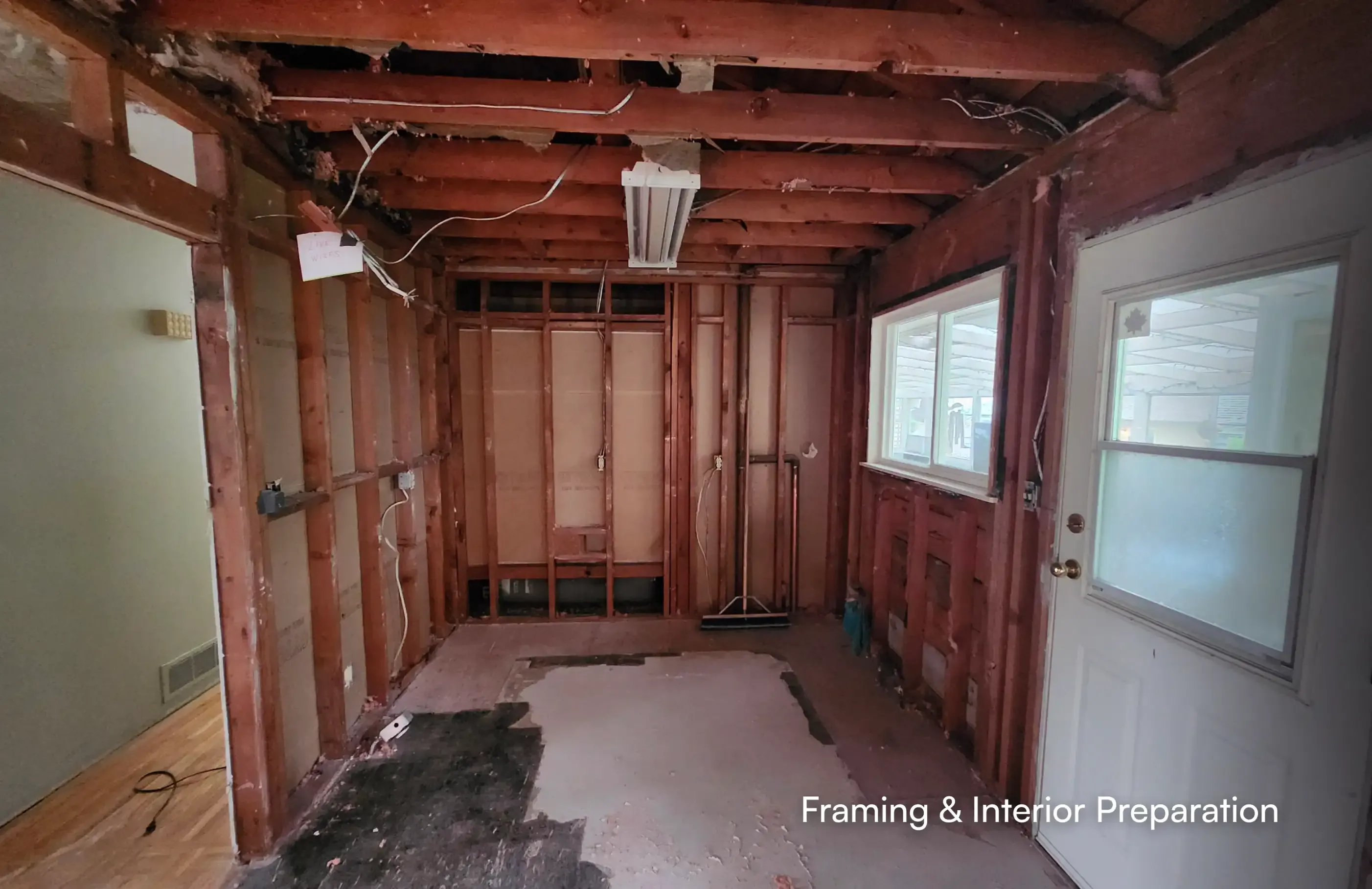 Fully gutted interior room displaying open wall framing, wiring, and structural prep work by Pacific Coast Contracting (PCC) for a Maple Ridge residential project.