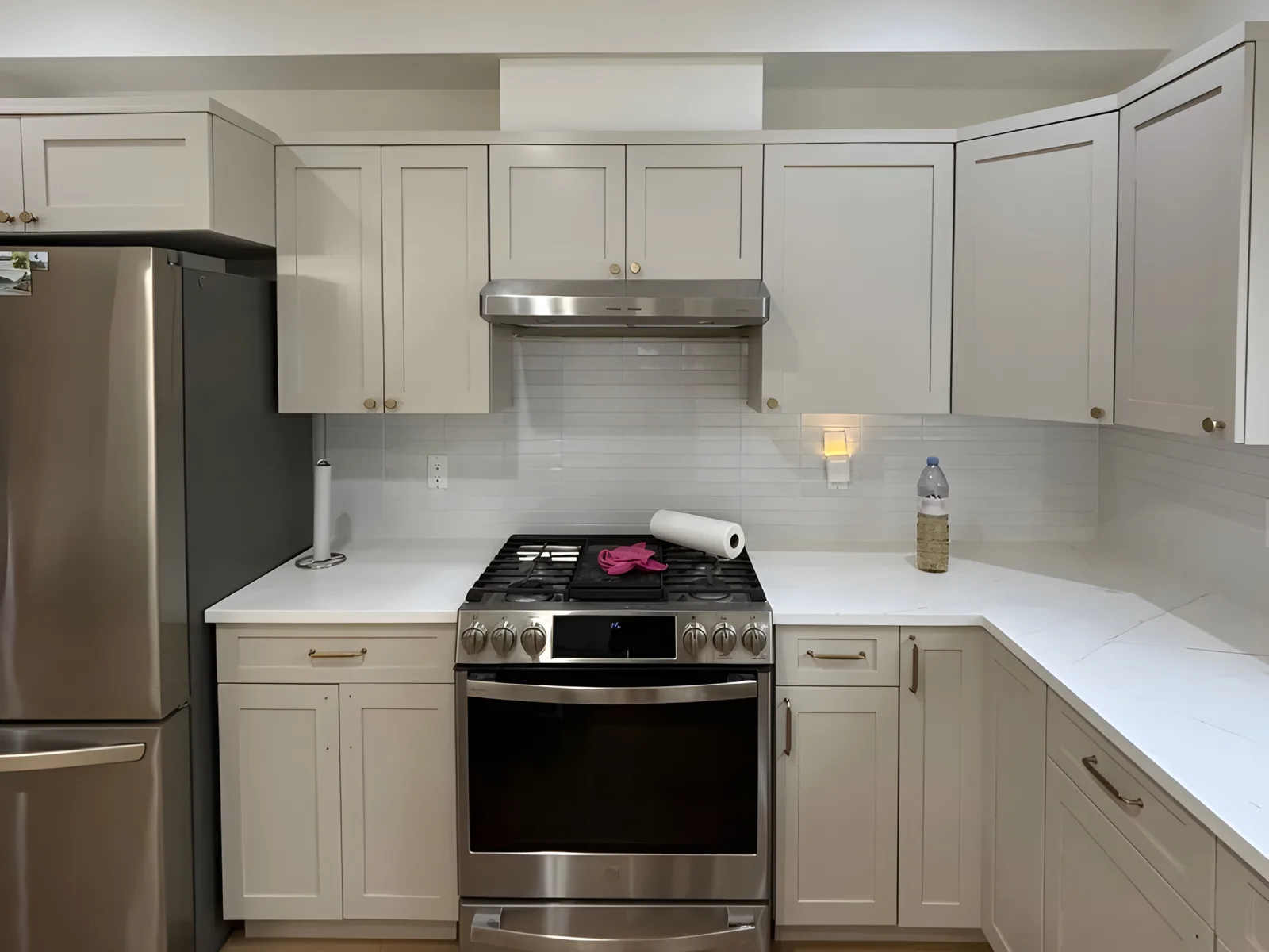 New light grey shaker kitchen cabinets with a stainless steel gas range, hood and white quartz countertop in a Billy Brown Road, Langley, BC kitchen renovation by PCC Renovations.