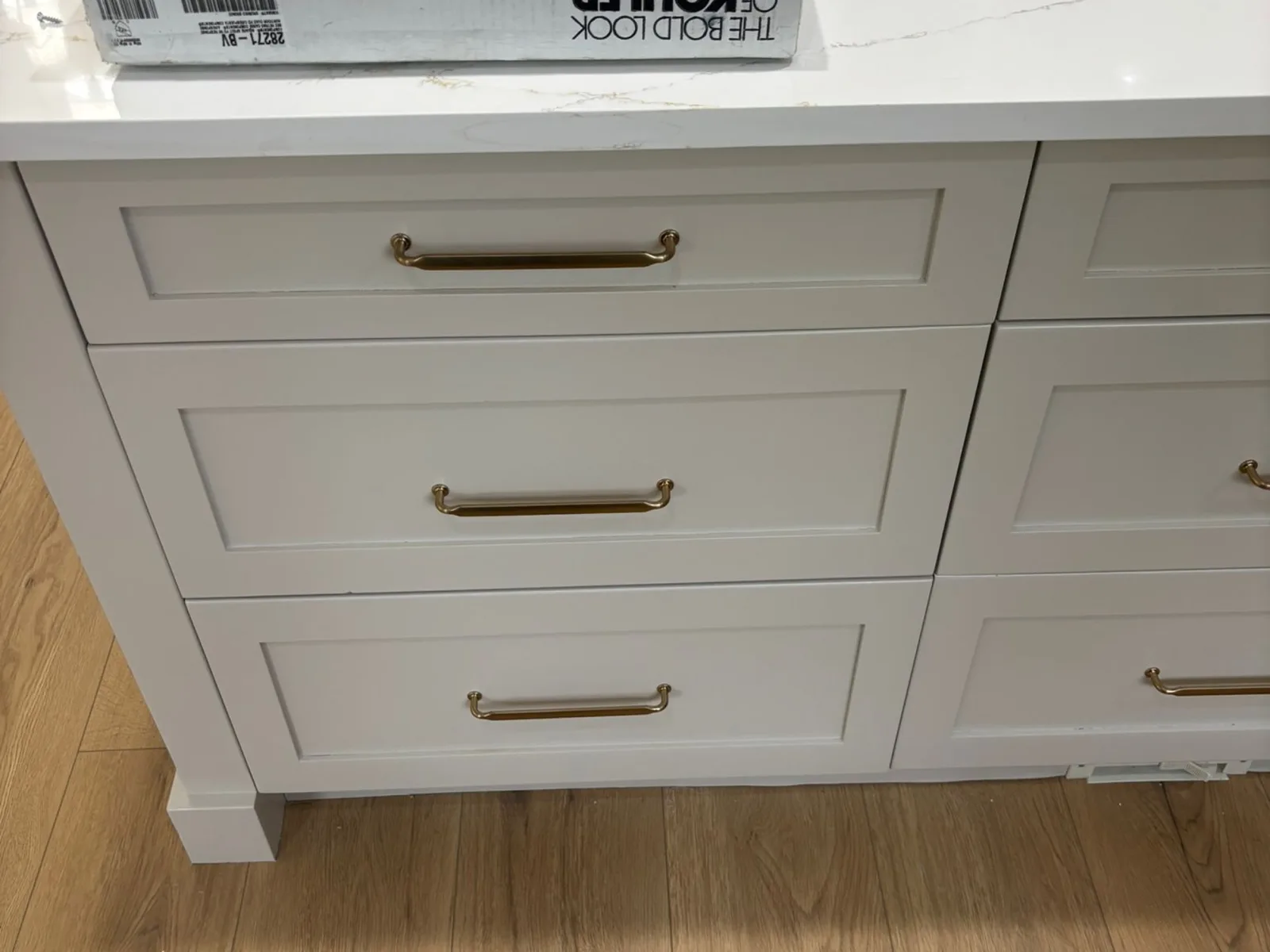 Close-up of white shaker drawer cabinets with brass pulls and a quartz countertop in a Billy Brown Road, Langley, BC kitchen renovation by PCC Renovations.