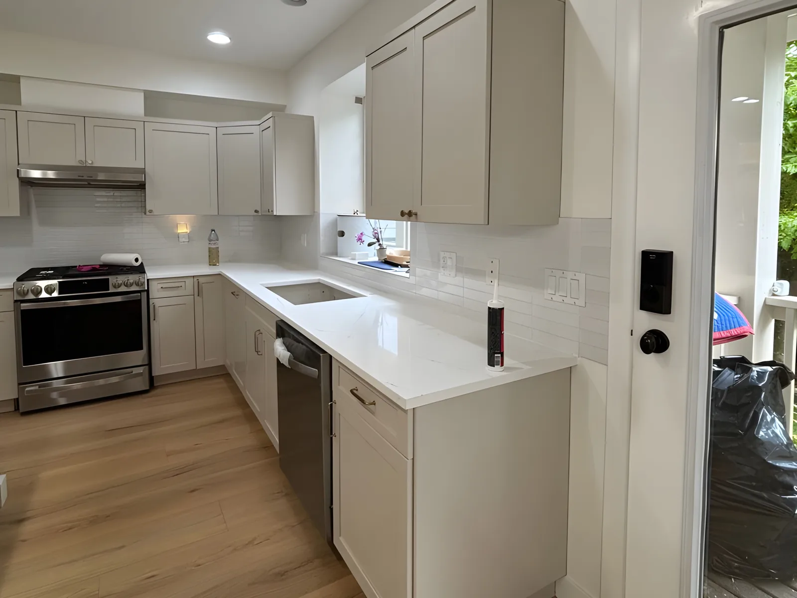 Kitchen layout with an undermount sink, quartz countertop, dishwasher and new cabinets in a Billy Brown Road, Langley, BC kitchen renovation by PCC Renovations.