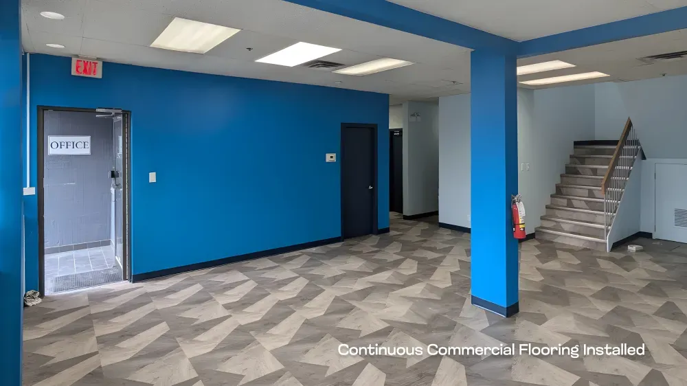 Wide view of a completed commercial office renovation featuring continuous patterned flooring and bright blue accent walls.