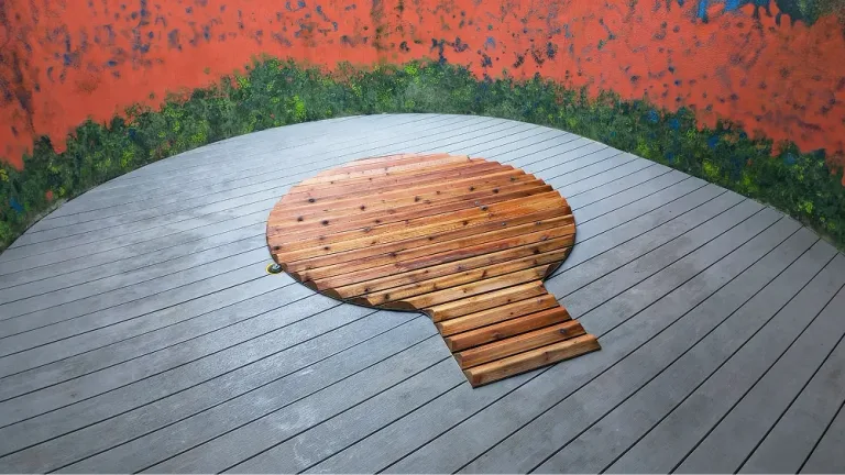 Top-down view of a custom cedar hot tub cover flush-mounted within a grey composite deck by PCC.