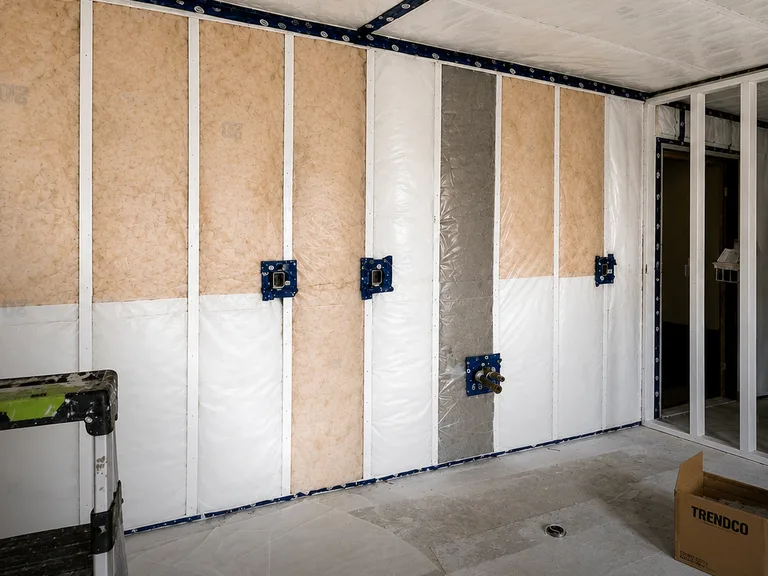 Wall insulation and vapour barrier with plumbing valves installed during a condo fire restoration in Chilliwack, BC by PCC Contracting.
