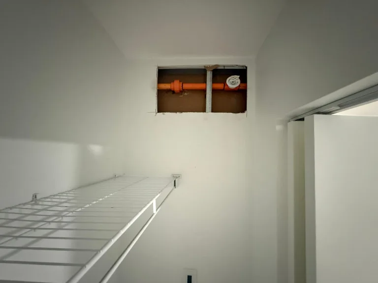 Open wall cavity exposing orange sprinkler piping above a closet shelf before drywall repair in Port Moody, BC by PCC Contracting. — before