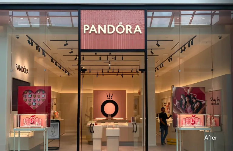 A well-lit Pandora jewelry store storefront inside a shopping mall after a repair or renovation. The store features a large glass entrance, bright interior lighting, a prominent pink tile sign above the door, and several display cases. A person is visible inside the store near the right display window. The word "After" is overlaid in the bottom right corner. โ after