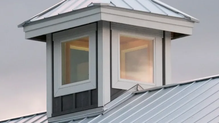 A standing-seam metal roof with a windowed cupola on a residential home